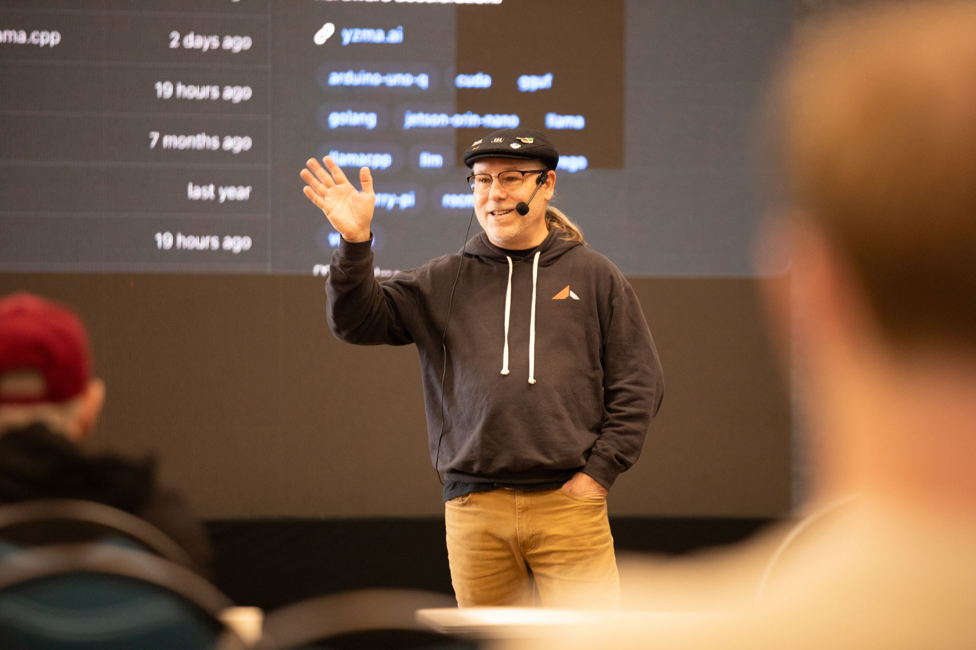 GopherCon LATAM 2026 — Bill Kennedy waving to the room in front of a list of local AI projects.