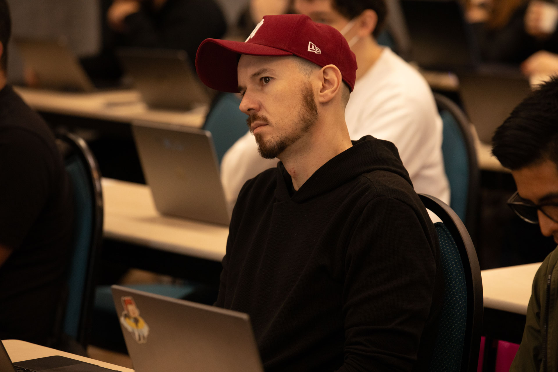GopherCon LATAM 2026 — an attendee in a red cap concentrating on the session.