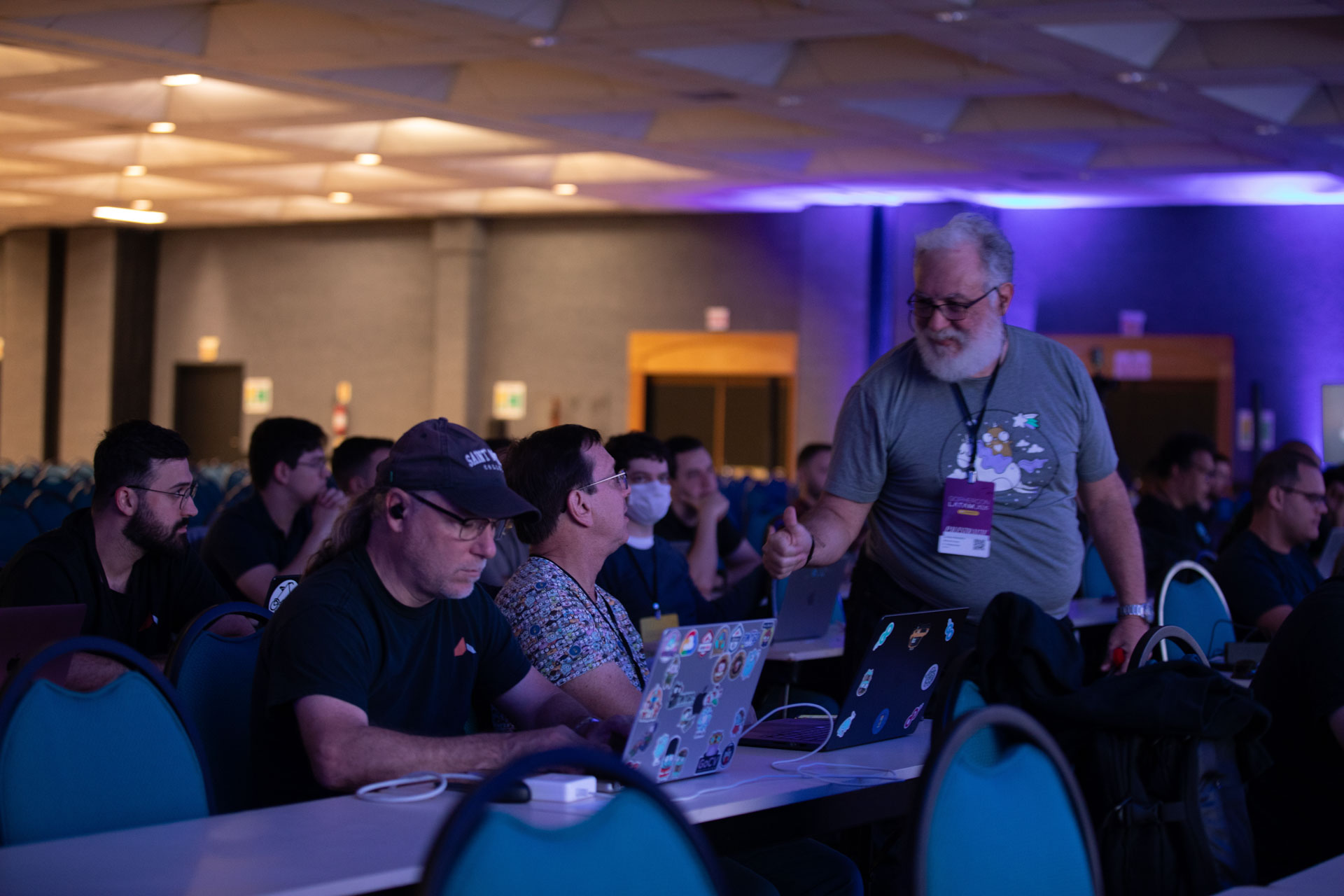 GopherCon LATAM 2026 — Bill Kennedy chatting with an attendee between sessions in the ballroom.