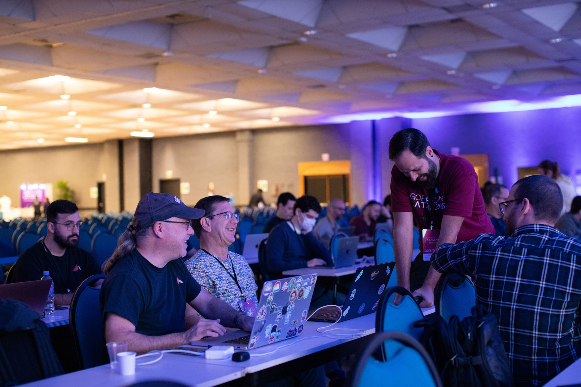 GopherCon LATAM 2026 — an organizer stopping by Bill Kennedy's table during a talk.