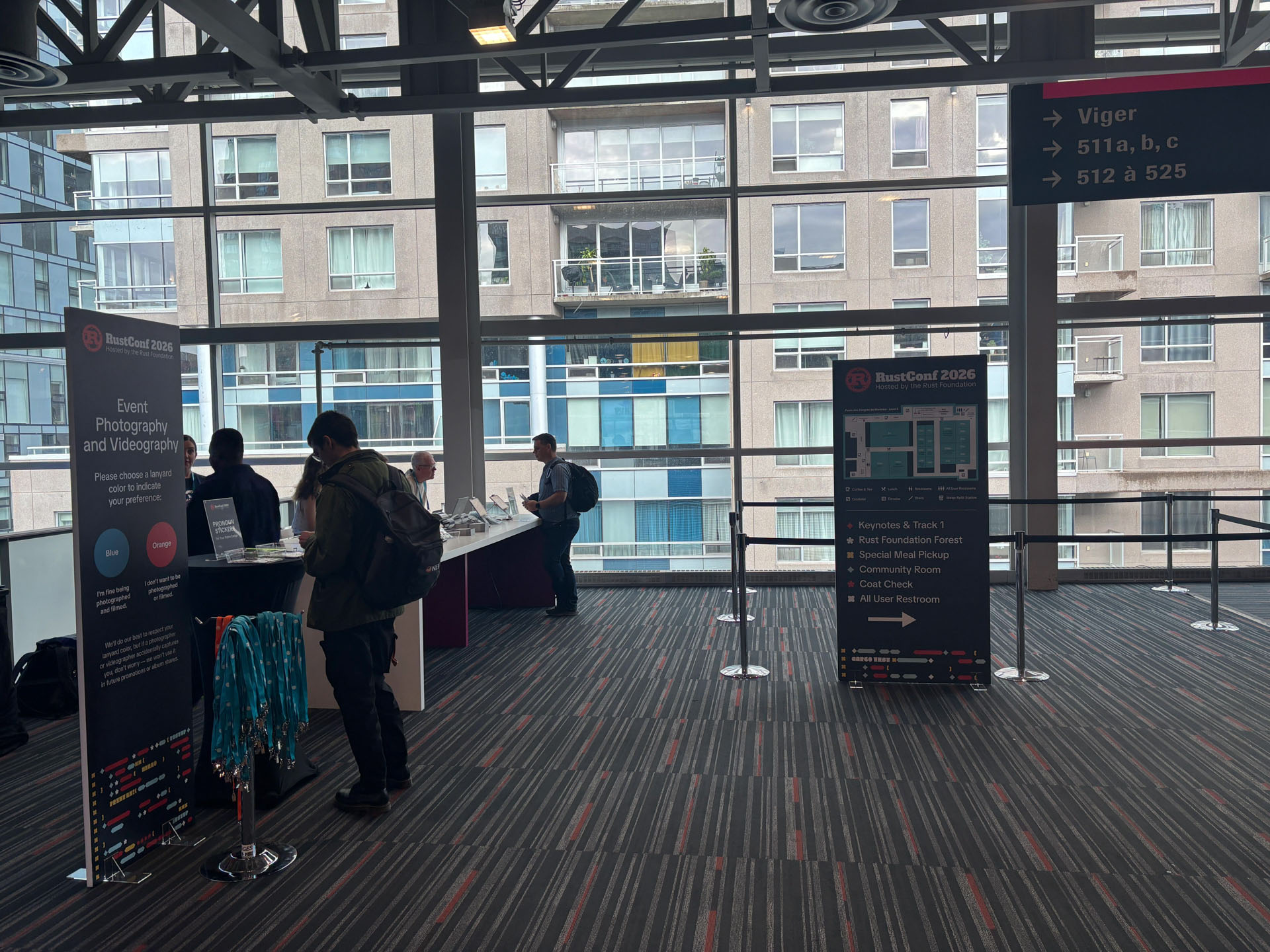 RustConf 2026 — attendees picking up lanyards and badges at the registration desk.