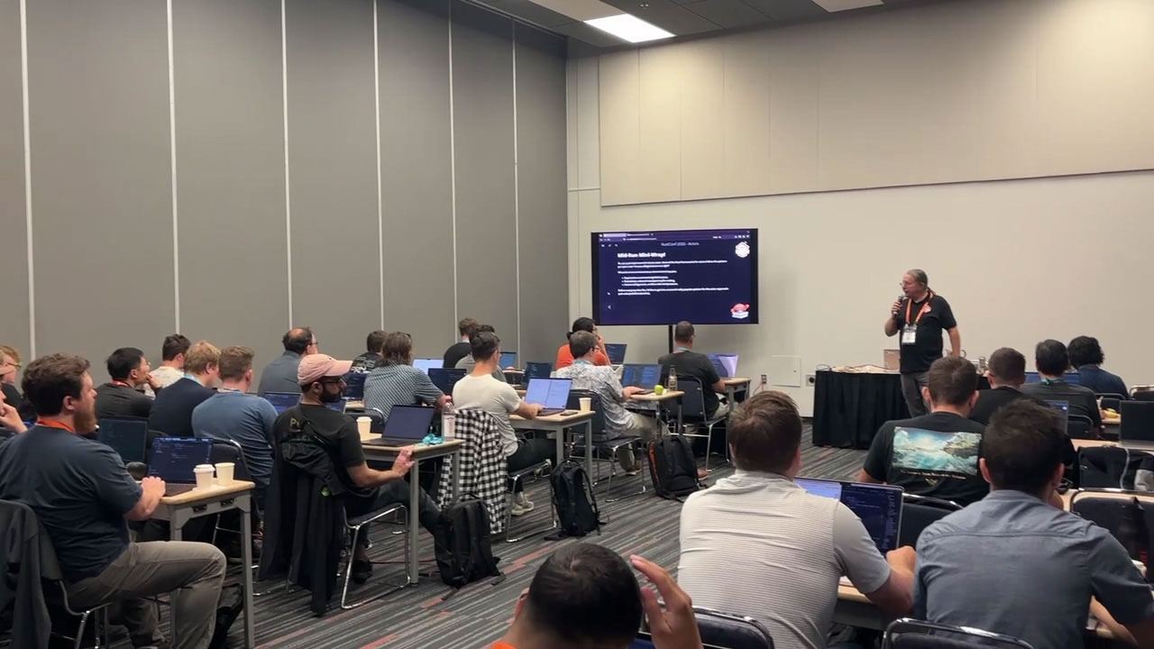 RustConf 2026 — Herbert Wolverson wrapping up a workshop module beside the screen.