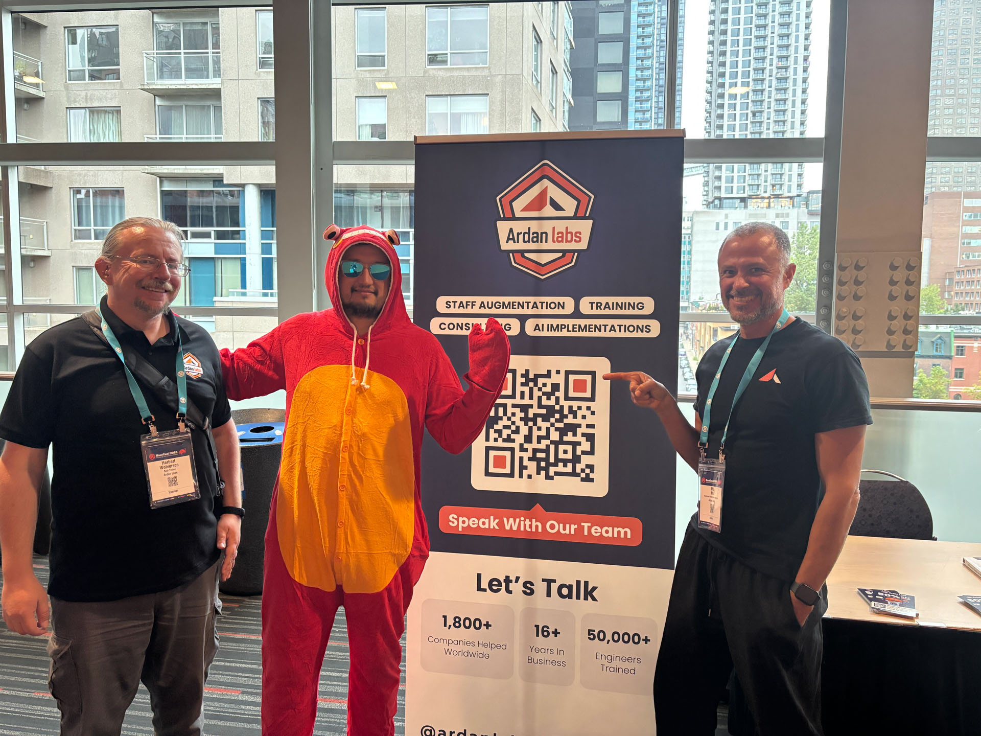 RustConf 2026 — Herbert Wolverson and MJ at the booth with an attendee in a Crab costume.