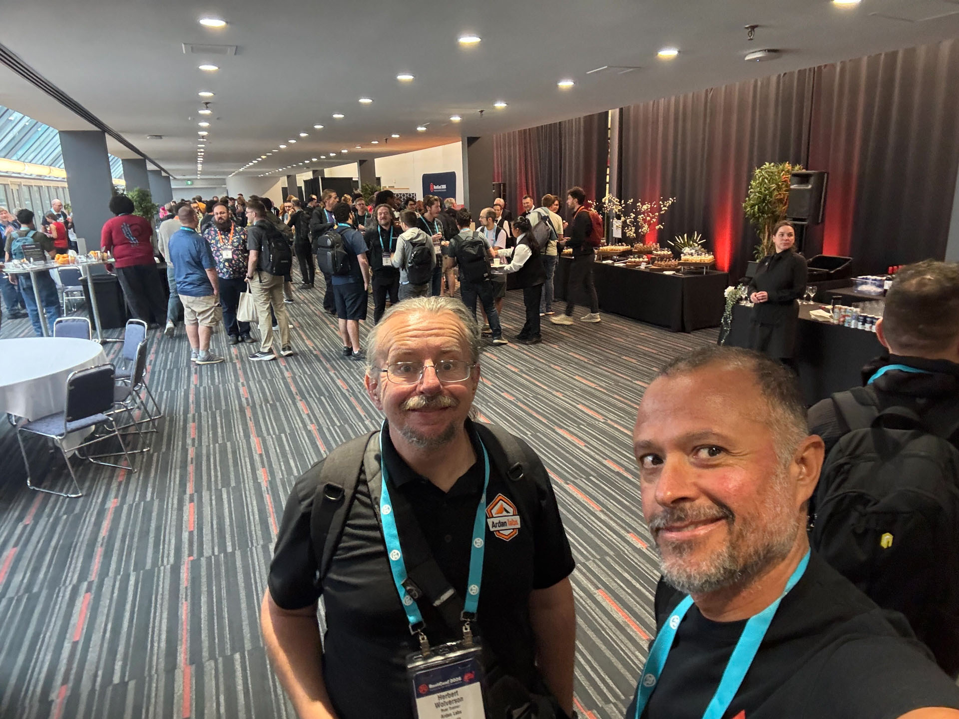 RustConf 2026 — Herbert Wolverson and MJ mingling with attendees at the evening reception.