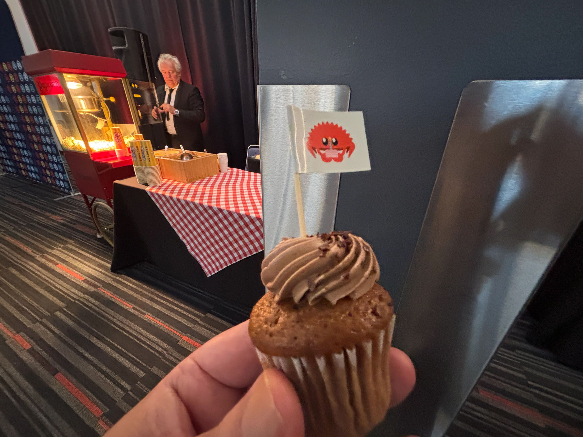 RustConf 2026 — a chocolate cupcake with a Rust flag in front of the popcorn cart.