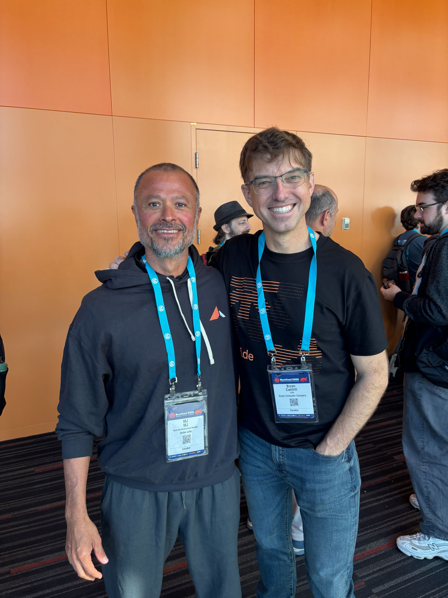 RustConf 2026 — MJ catching up with a fellow Rust developer in the hallway.