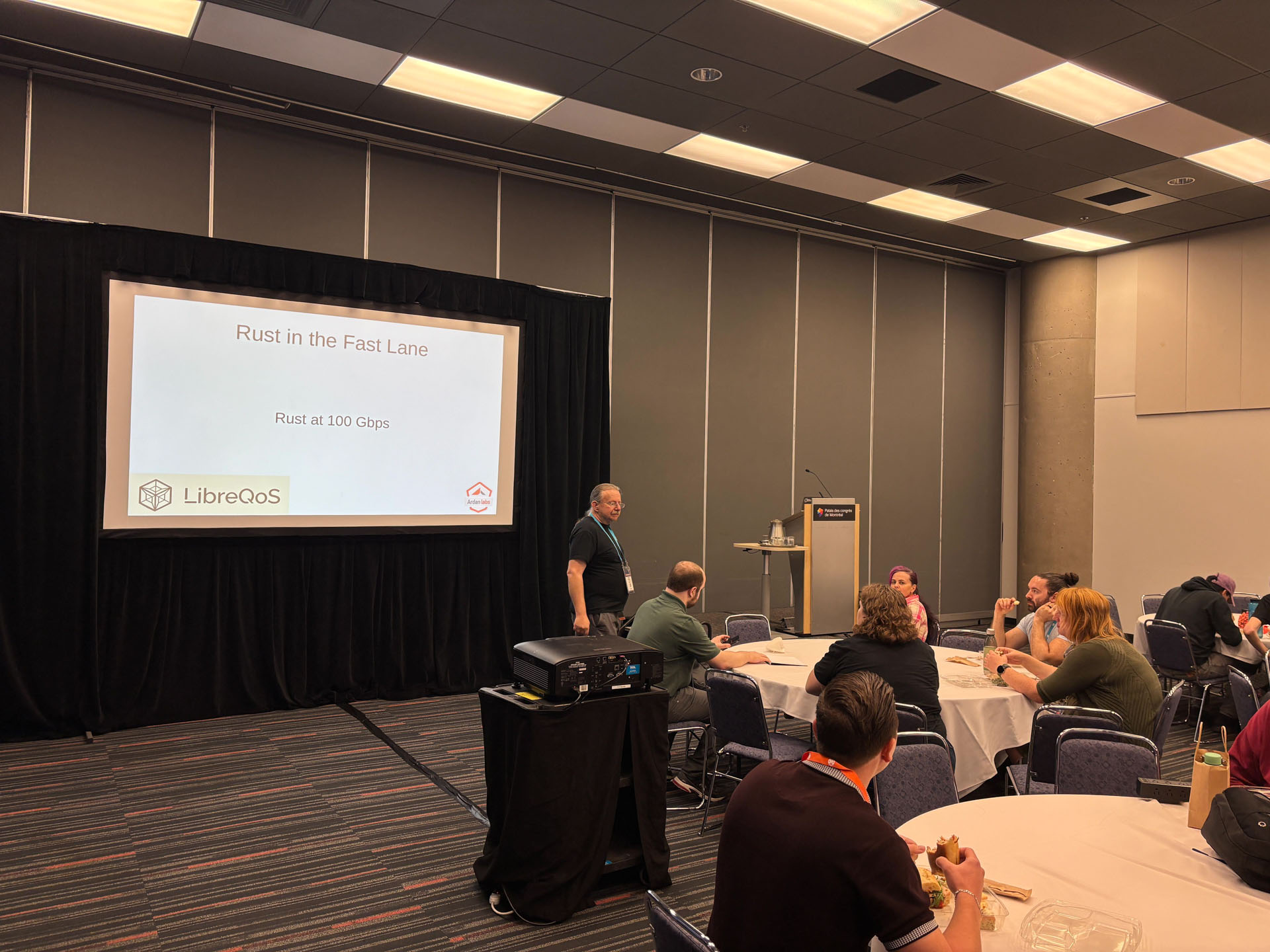 RustConf 2026 — Herbert Wolverson beginning his LibreQoS talk in the community room.