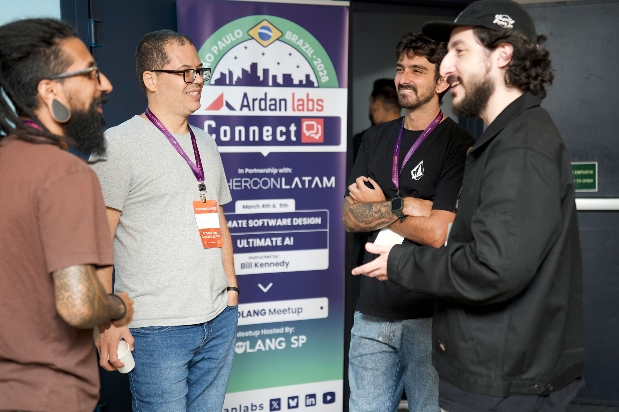 Attendees networking at Ardan Labs Connect in São Paulo beside the event banner for Ultimate Software Design and Ultimate AI